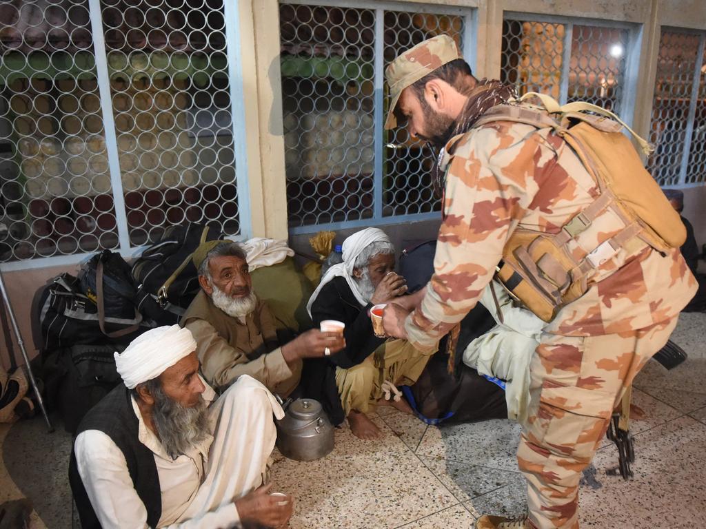 A soldier hands out tea to freed train passengers gathered at the Mach railway station, which has been turned into a makeshift hospital. Picture: AFP