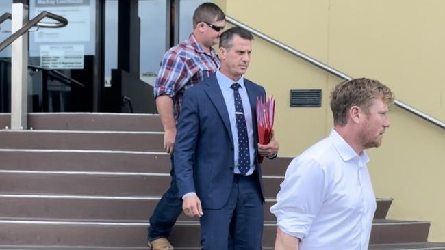 Derek Gordon Young, 36, (back) hides behind his solicitor Marcus Hahn, of McKay's Solicitors, as he leave Mackay Magistrates Court with barrister Isaac Munsie (right).