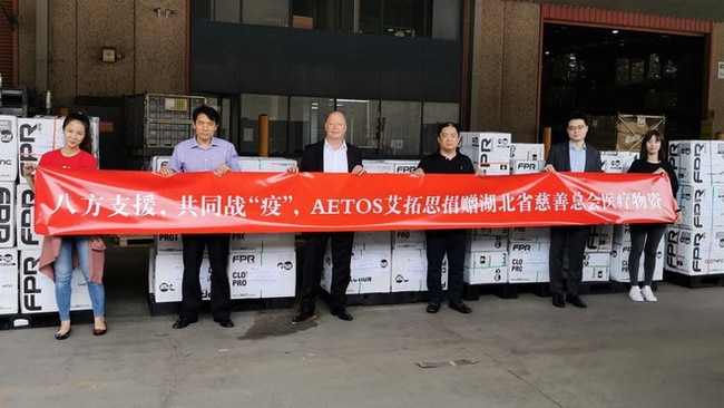 Hills councillor Mike Thomas (centre) with AETOS Capital Group collegues in front of 4000 sets of medical clothing sent to China during COVID-19.