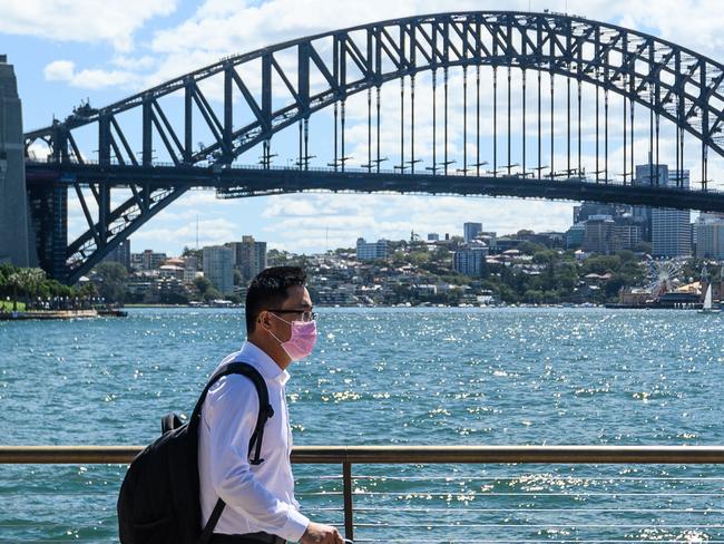 A man wearing a protective face mask in front of the Sydney Harbour Bridge, Sydney, Friday, March 13, 2020. NSW is ramping up efforts to contain the spread of COVID-19 virus, with fears as many as 1.6 million could be infected if the pace of the outbreak continues. (AAP Image/James Gourley) NO ARCHIVING