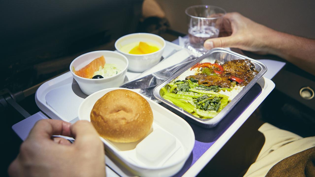 Passenger enjoying dinner in economy class during long haul flight.