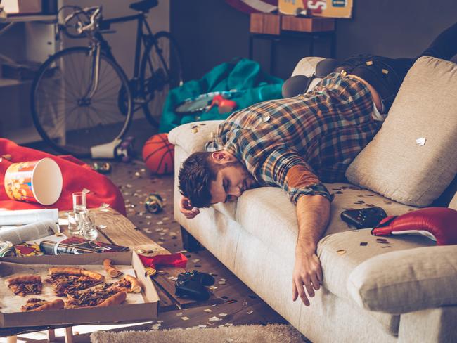 Young handsome man passed out on sofa in messy room after party