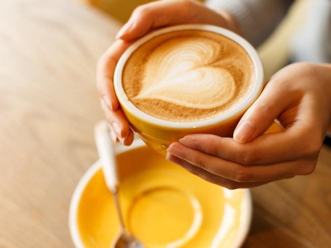 lady's hands hold cup filled with something heart-shaped