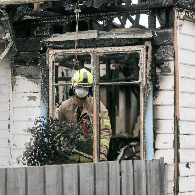 Firefighters shovel ash and coals out of a window at a house destroyed by fire at Mayfield, Launceston. Picture: PATRICK GEE