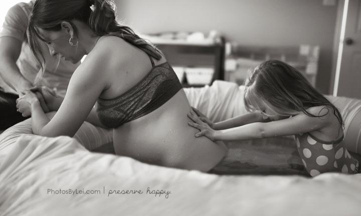 Daughter supporting mother in childbirth - This was a beautiful birth filled with questions and love and wonder. The pictures capture all that and more. My client’s 7 year old daughter is providing pressure to her mother’s lower back. She so calmly and sweetly came into the room where her mother was birthing and genuinely wanted to help. Later her mother told me how comforting it was to have her there, and how much she admired the nurturing nature her daughter possessed.”