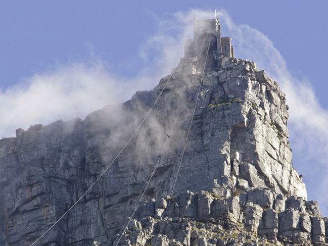 FILE -- In this Thursday Jan. 15, 2009 file photo cable cars ascend and descend below the top of Table Mountain in Cape Town, South Africa. In a dramatic overnight operation, emergency responders have descended on ropes from a cable car on South Africa's Table Mountain to recover the bodies of two male climbers, including a Japanese citizen, who died after falling from a cliff, it was reported Tuesday, Jan. 2, 2018. (AP Photo/Schalk van Zuydam, File)