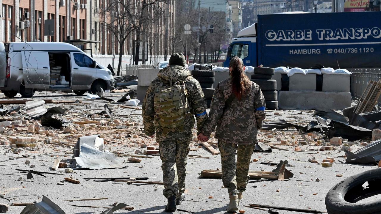 A couple of Ukrainian soldiers walks hand in hand amid Russian invasion of Ukraine in Kyiv on March 17 as Russian troops try to encircle the Ukrainian capital as part of their slow-moving offensive. Picture: Sergei SUPINSKY / AFP