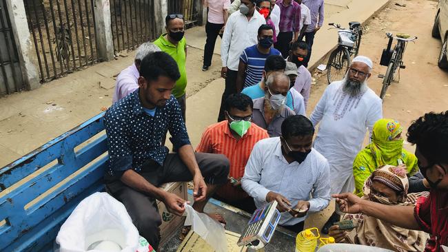 People line up to shop for essential items from a roadside truck in Dhaka, Bangladesh on Wednesday. Picture: AP