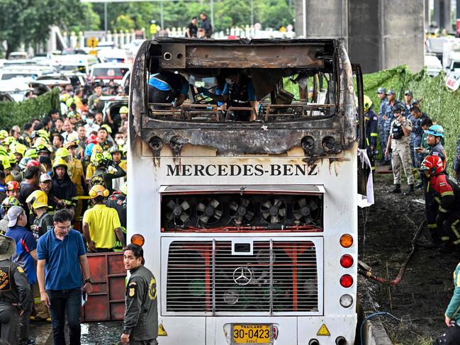 Rescue workers and firefighters surround a burnt-out bus that was carrying students and teachers on the outskirts of Bangkok on October 1, 2024. A devastating fire tore through a Thai bus carrying 44 students and teachers on a school trip on October 1, officials said, with up to 25 feared dead. (Photo by Manan VATSYAYANA / AFP)