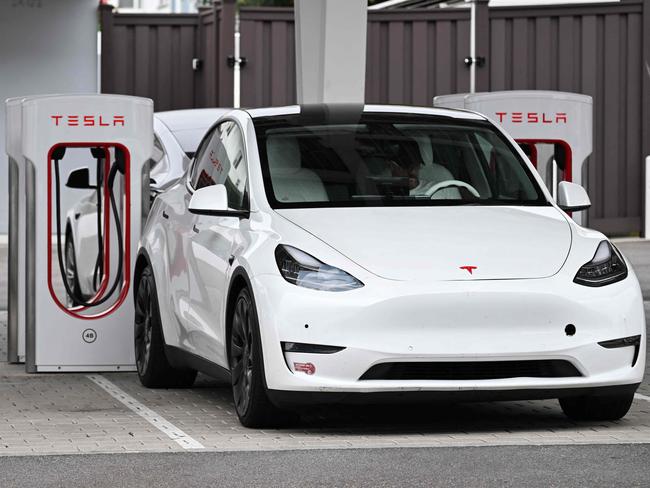 (FILES) A Tesla electric vehicle charges at a Tesla Supercharger location in Santa Monica, California on May 15, 2024. Tesla reported a hefty drop in second-quarter profits on July 23, 2024 due to the effect of price cuts while spending aggressively on artificial intelligence and other technology. Elon Musk's electric vehicle company reported profits of $1.5 billion, down 45 percent, on revenues of $25.5 billion, up two percent. (Photo by Patrick T. Fallon / AFP)