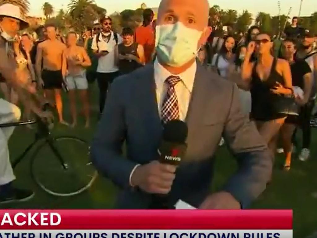 People gather around and play for the camera as a 7 NEWS reporter does a live cross at St Kilda Beach