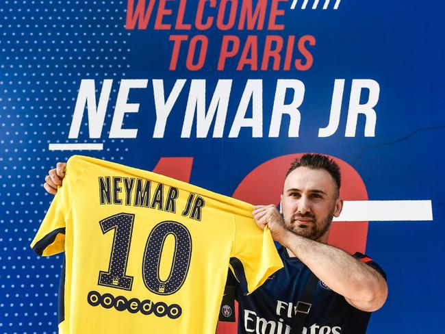 A PSG fan holds a PSG yellow away jersey marked with the number 10 and Neymar’s name.