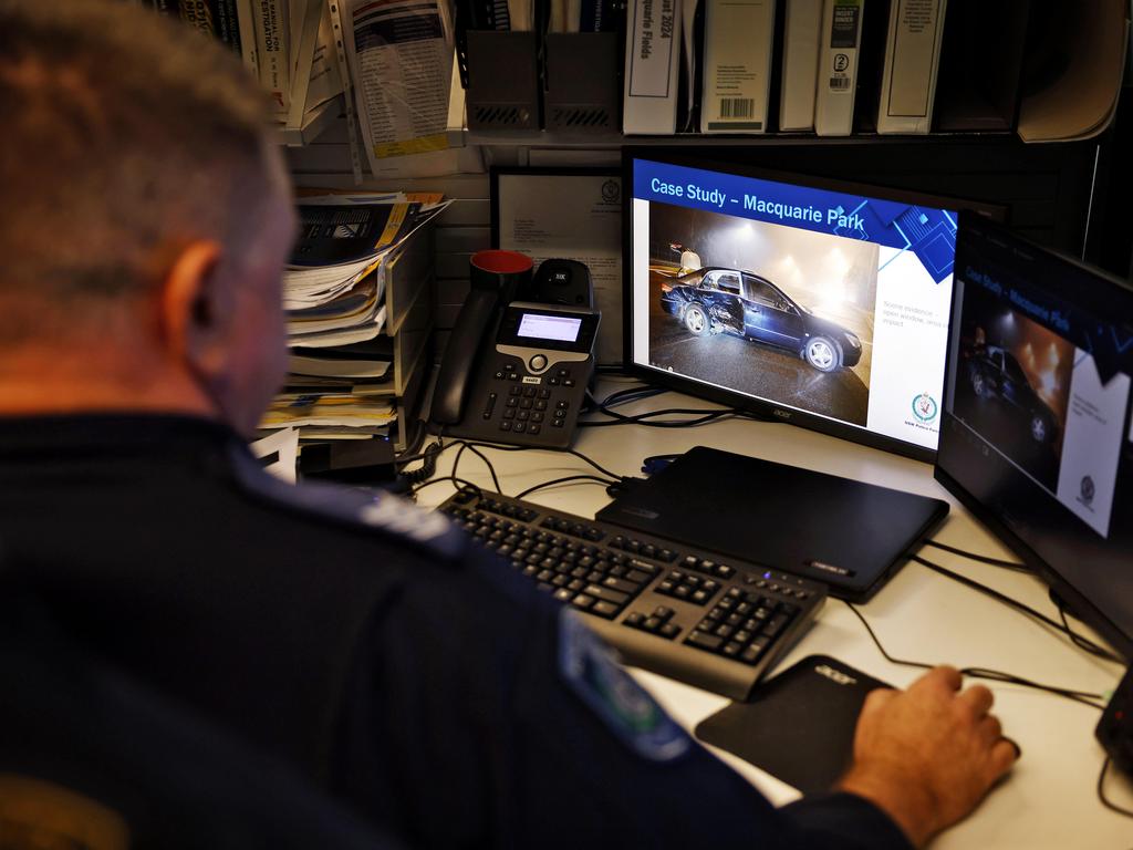 Sergeant Brett Hobbins examines pictures from a crash scene. Picture: Sam Ruttyn