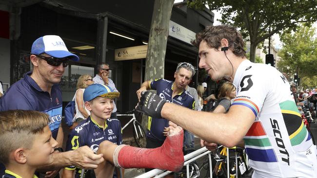 Defending Tour Down Under champion Daryl Impey signs the broken leg of Oscar Pietsch 11yrs from Woodville West at the start line. Picture SARAH REED