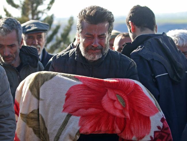 A man carries the body of child who was killed with his parents in a deadly earthquake, during a funeral in the village of Gozebasi in Adiyaman province, Turkey. Picture: Reuters