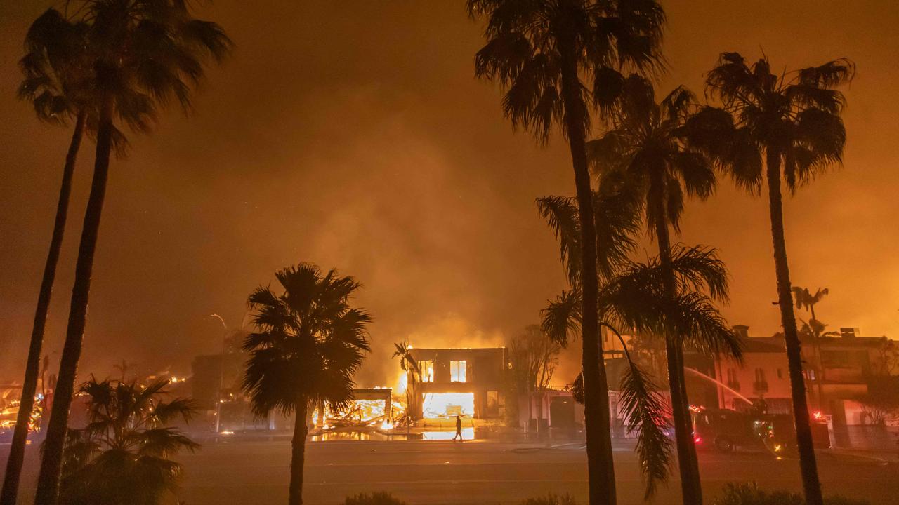 A firefighter watches the flames from the Palisades Fire burning homes on the Pacific Coast Highway amid a powerful windstorm on January 8, 2025 in Los Angeles, California. (Photo by Apu Gomes / GETTY IMAGES NORTH AMERICA)