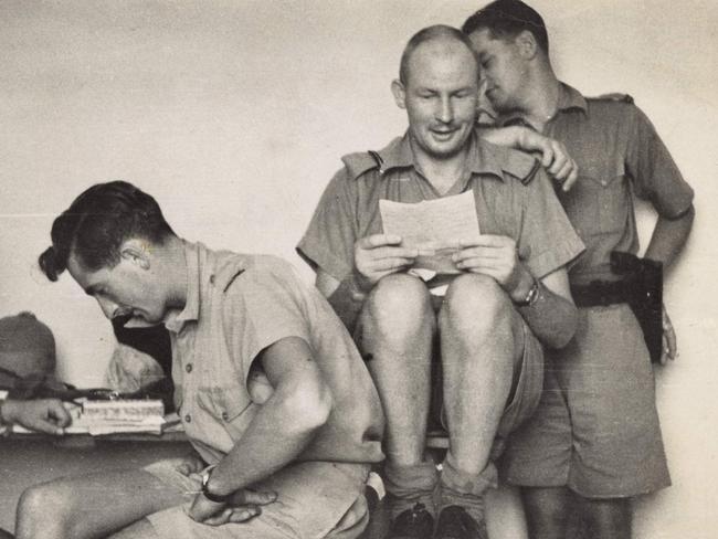 Squadron Leader John Francis Jackson reading a letter in the company of members of No. 3 Squadron. Picture: Australian War Memorial