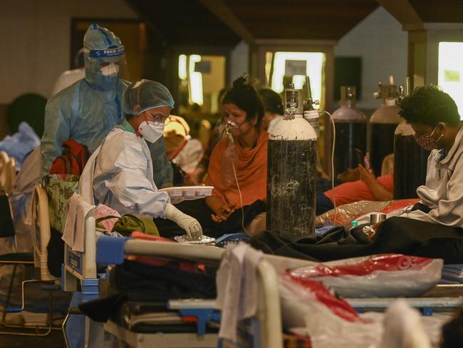 Health workers wearing personal protective equipment attend to COVID-19 patients inside a banquet hall temporarily converted into a COVID care centre in New Delhi. Picture: AFP