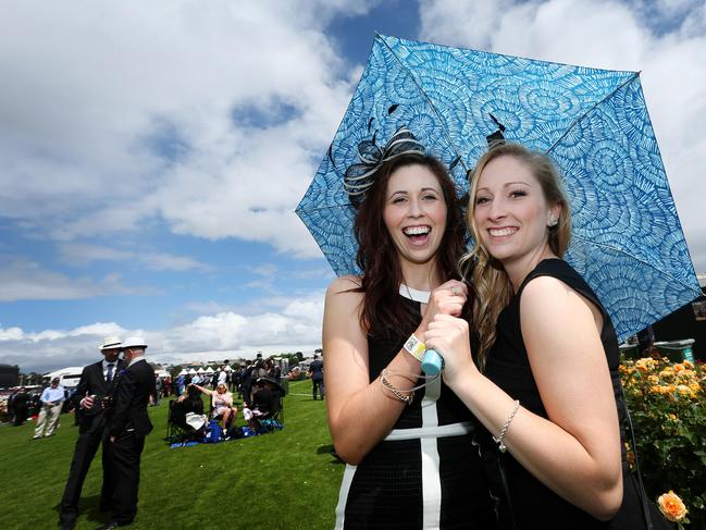 2014 AAMI Victoria Derby Day, Flemington, Victoria. Sarah Maher, 26, and Kerry Lightowler, 26, hide from a quick sun shower. Picture: Mark Stewart