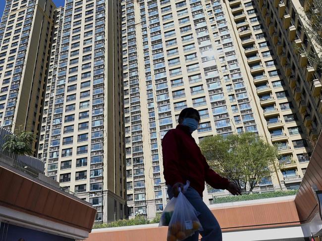 A woman walks in front of a housing complex by Chinese property developer Evergrande in Beijing on October 21, 2021. (Photo by Noel Celis / AFP)