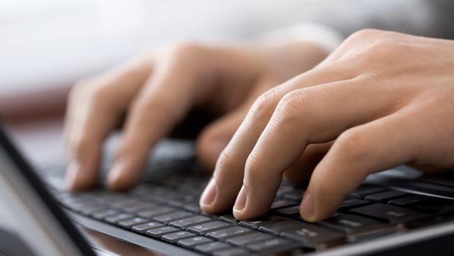 Close-up of male fingers typing a business document on the black laptop