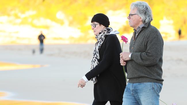 John Ruszczyk and partner Maryan Heffernan place a flower in the surf. Picture: John Grainger