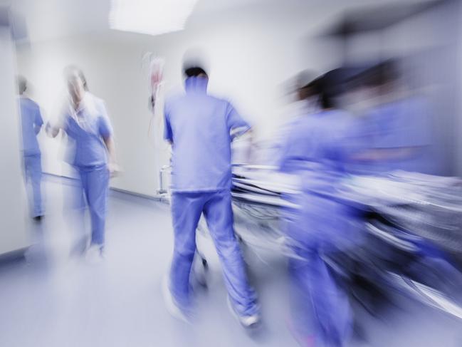 Doctors and nurses pulling hospital trolley,