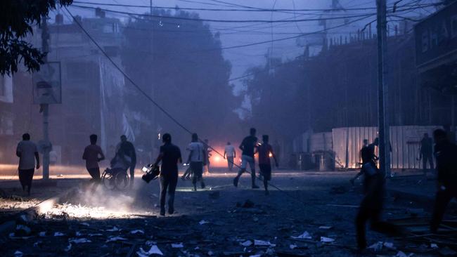 People run along a debris-strewn street following Israeli air strikes in Gaza City on October 7, 2023. Picture: AFP