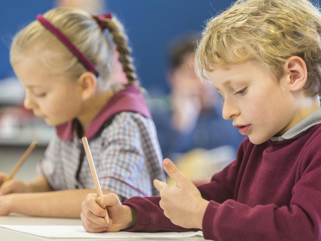 Happy young school boy in a classroom counting on his fingers