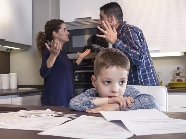 Sad child suffering and his parents having hard discussion in a home kitchen by couple difficulties. Family problems concept.. Pic Istock