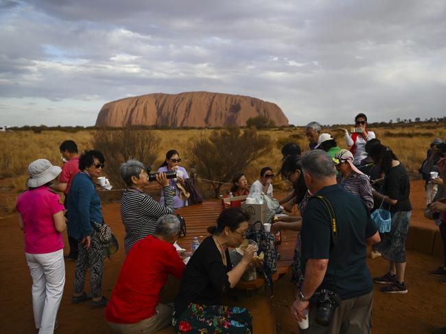 Wind gusts swept through as tourists take pictures of Uluru, also known as Ayers Rock from the dedicated sunset area near Uluru-Kata Tjuta National Park in the Northern Territory this week. Picture: AAP