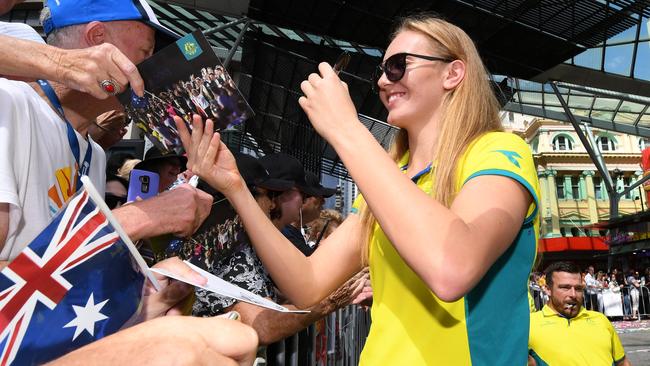 Commonwealth Games gold medalist swimmer Ariarne Titmus signs autographs during a street parade to honour the Games' athletes through central Brisbane (AAP Image/Dan Peled)