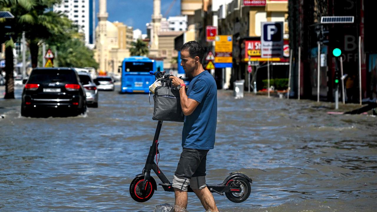 A man crosses a flooded street following heavy rains in Sharjah on April 17, 2024. (Photo by Ahmed RAMAZAN / AFP)