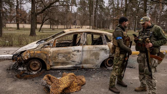 Members of the Ukrainian military stand by a destroyed vehicle on April 6 in Bucha.