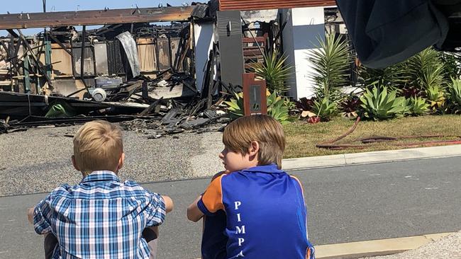 Local boys view the damage to their neighbour’s house in Pimpama after it was gutted by fire this morning. Picture: Annie Perets.