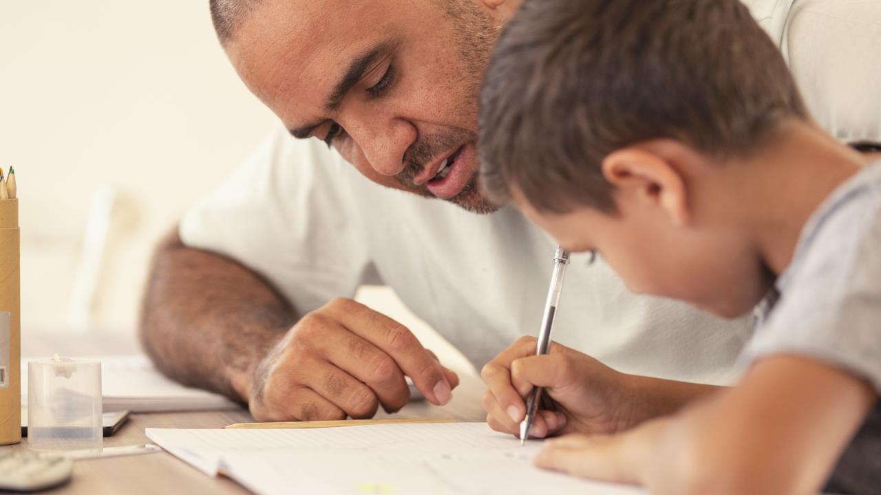 Young Aboriginal boy doing homework with the help of his father.