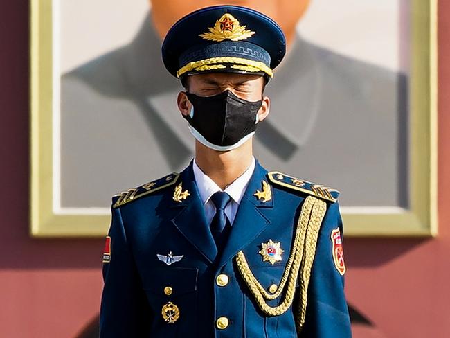 BEIJING, CHINA - APRIL 04: A Chinese paramilitary policeman wears a protective mask stands in front of a portrait of late communist leader Mao Zedong reacts during a national mourning to mourn victims of COVID-19 on April 04, 2020 in Beijing, China. China will hold a national mourning on Saturday for martyrs who died in the fight against the novel coronavirus and compatriots died of COVID-19, according to the State Council. During the commemoration, national flags will fly at half-mast across the country as well as in all Chinese embassies and consulates abroad. Public recreational activities will be suspended. At 10:00 am on Saturday, the country will observe three minutes of silence to mourn for the diseased, while air raid sirens and horns of automobiles, trains and ships will wail in grief.  (Photo by Lintao Zhang/Getty Images)