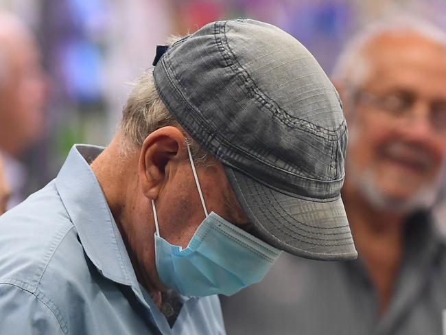 A man wears a face mask as a preventative measure against corona virus at a checkout in a Woolworths supermarket in Coburg, Melbourne, Thursday, March 19, 2020. For a second day, Woolworths has allowed the elderly access to early morning shopping ahead of the general public due to panic buying as Covid-19 fears mount. (AAP Image/James Ross) NO ARCHIVING