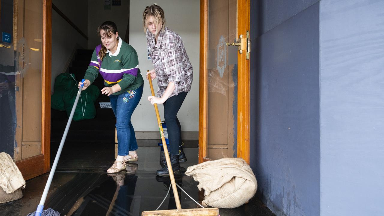 Madi Quinn (left) and Sophie Fitzgerald clean up after flood water went through The National Hotel in Russell St, Saturday, February 26, 2022. Picture: Kevin Farmer