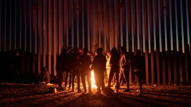 Migrants gather around a fire at the US-Mexico border fence in Arizona, which has been closed following a huge influx of people crossing. Picture: Eric Thayer/Bloomberg via Getty Images