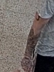 The man has distinctive tattoos on his right arm.