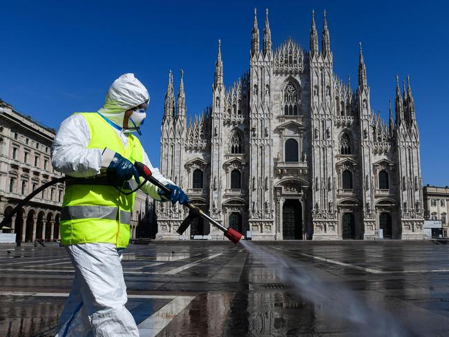 TOPSHOT - An employee wearing protective gear, working for environmental services company AMSA, sprays disinfectant on Piazza Duomo in Milan, on March 31, 2020 during the country's lockdown aimed at curbing the spread of the COVID-19 infection, caused by the novel coronavirus. (Photo by Piero Cruciatti / AFP)