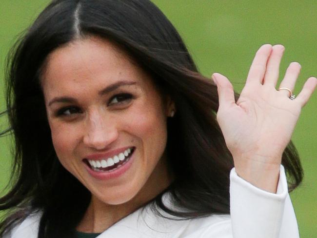 Britain's Prince Harry's fiancee US actress Meghan Markle waves as she poses for a photograph in the Sunken Garden at Kensington Palace in west London on November 27, 2017, following the announcement of their engagement. Britain's Prince Harry will marry his US actress girlfriend Meghan Markle early next year after the couple became engaged earlier this month, Clarence House announced on Monday. / AFP PHOTO / Daniel LEAL-OLIVAS