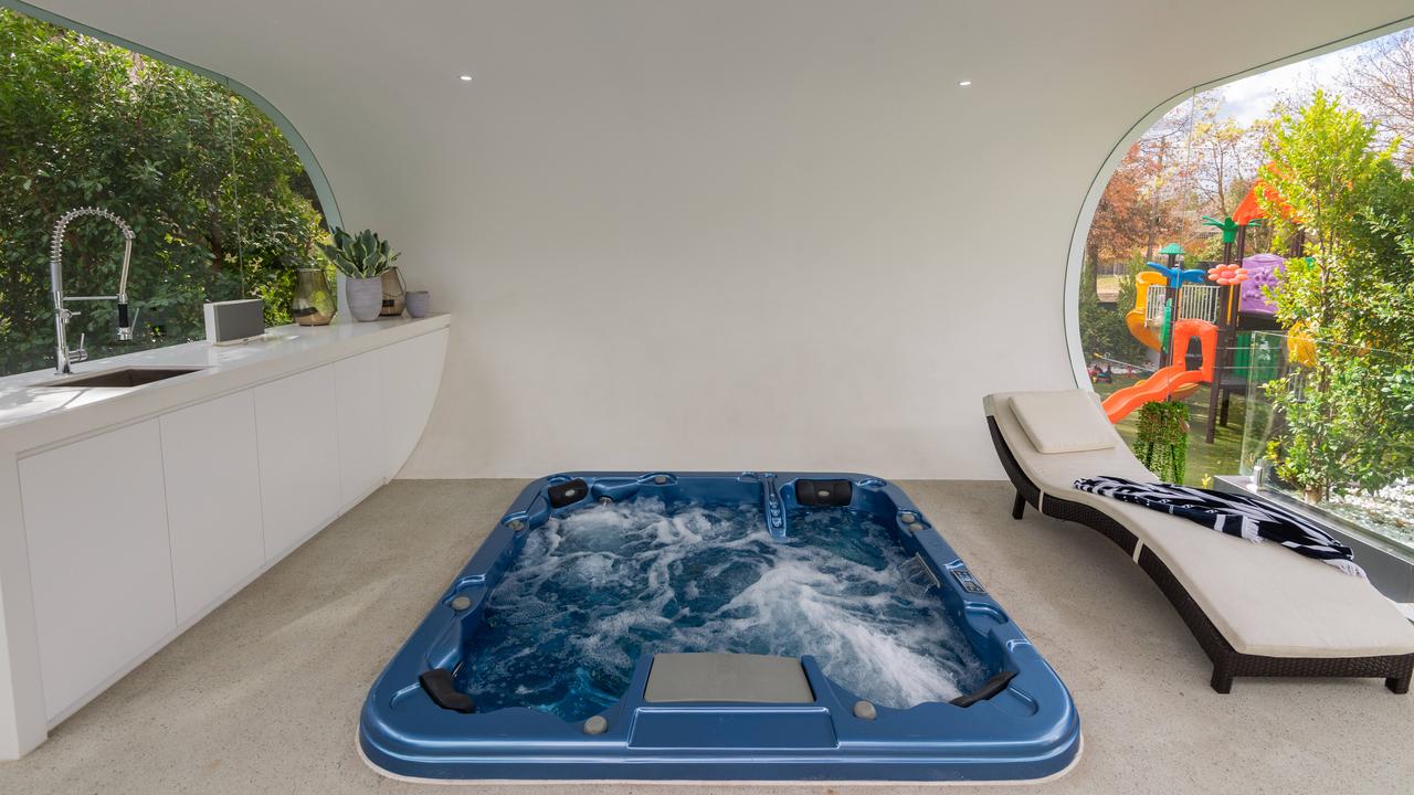 The white backyard “curl room” featuring a jacuzzi, with the private playground in the background. Picture: Jason Edwards