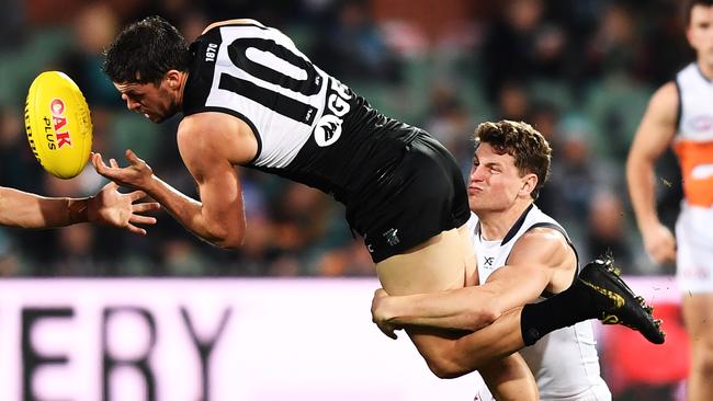 Travis Boak fires off a handball while being tackled by GWS’s Jacob Hopper. Picture: Mark Brake (Getty).