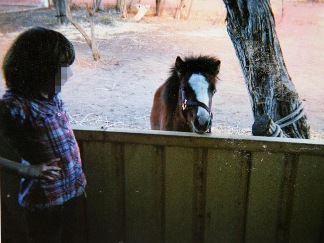 The farm: One of the Colt girls smiles at a pony kept in a makeshift pens on the farm. The Colts kept four ponies, as well as rabbits, cats and dogs and carers would later hear how children mutilated the animals.