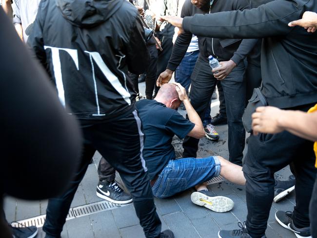 The man holds his head as he sits on the ground after he was carried by protesters. Picture: Getty