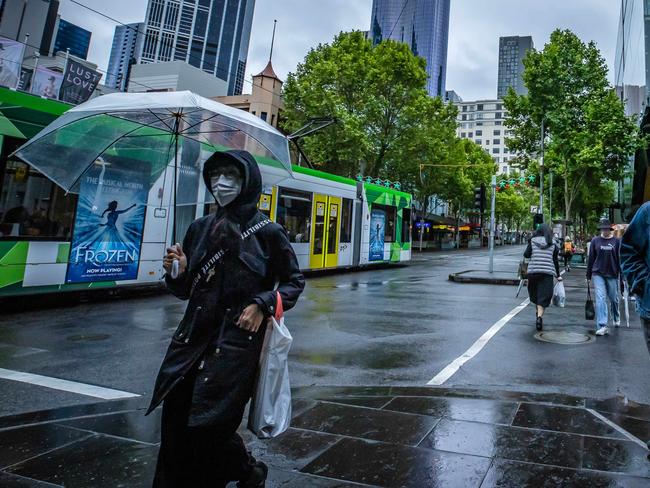 Gloomy weather hits Melbourne with rain and cold winds, pedestrians cross Lonsdale Street with umbrellas. Picture: Jason Edwards