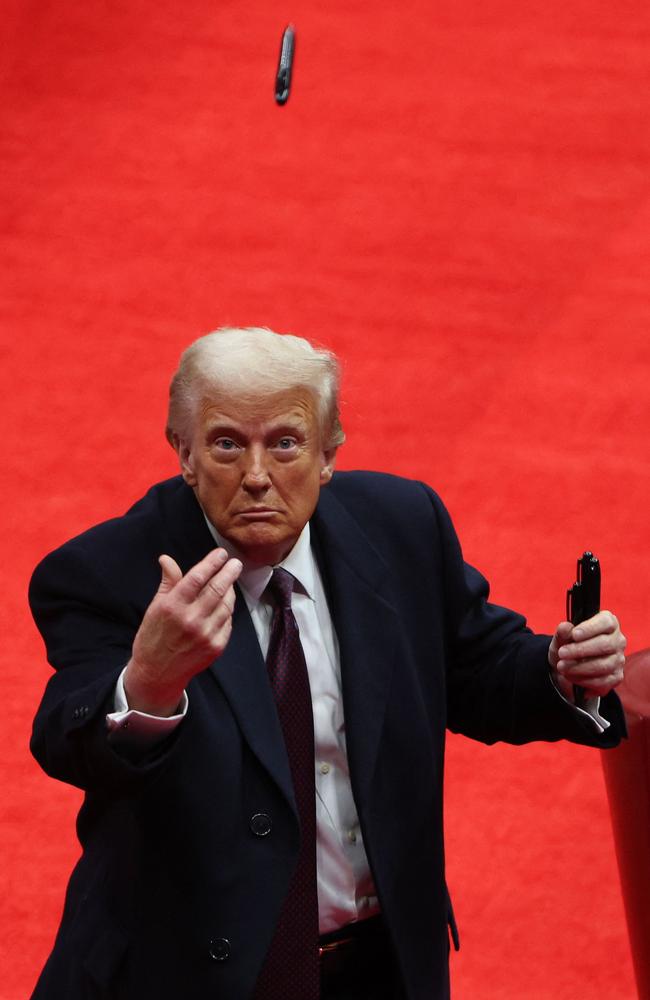 US President Donald Trump throws a pen after signing executive orders during the indoor inauguration parade. Picture: Getty Images/AFP