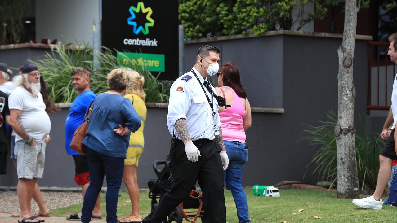 Officials from Centrelink speak to the lines of people waiting at Southport Centrelink. Picture: Adam Head.